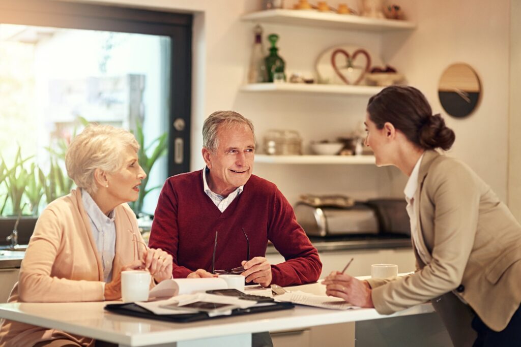 two senior citizens and a female medicare agent sitting at a table having a meeting