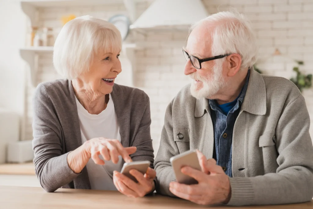 a senior citizen couple sitting next to each other with cell phones in their hand