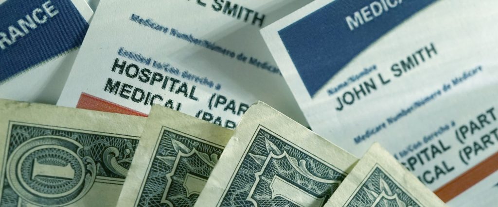 Medicare paperwork with four one-dollar bills laying on top